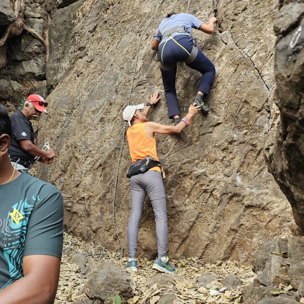 Group rock climbing on a rocky cliff.