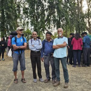 Group standing outdoors with trees in background.