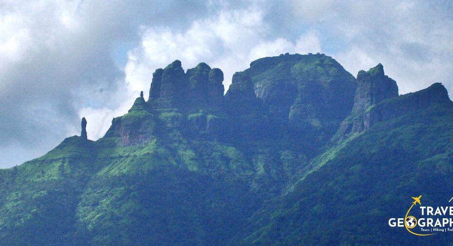Green mountain peak under cloudy sky