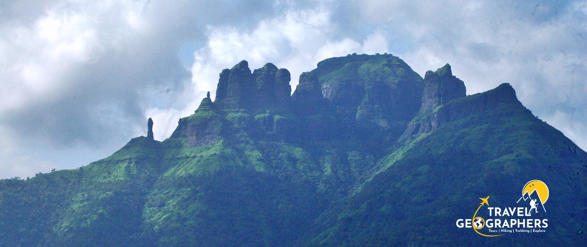 Green mountain peak under cloudy sky