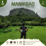 Hiker viewing Manikgad mountain lush landscape.