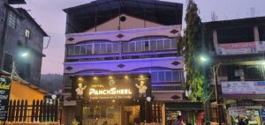 Hotel Panchsheel exterior at dusk, illuminated signage.