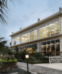 Modern glass building with garden at dusk.