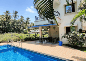 Tropical villa with balcony, pool, and palm trees.