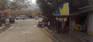 Small market with vehicles on road.