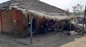 Traditional rural house with motorbike and thatched roof.
