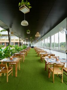 Outdoor dining area with wooden tables and greenery.
