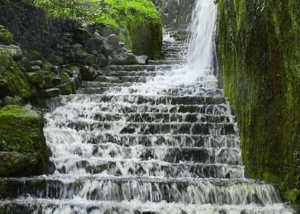 Waterfall cascading down mossy stone steps.