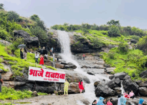 Scenic waterfall with people visiting, lush greenery around.