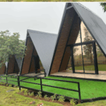 Modern A-frame cabins with glass fronts and greenery.